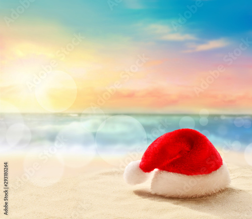 Christmas holidays concept. Santa claus hat on summer sand beach