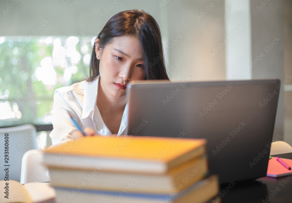 Young Asian woman using laptop computer and tablet PC to working in the modern co working space Young Asian woman using laptop computer and tablet PC to working in the modern co working space