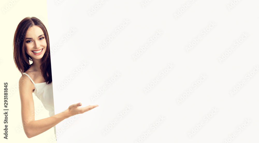 Happy smiling woman in white casual smart clothing, showing empty blank signboard with copy space area for text or slogan, isolated over yellow Happy smiling woman in white casual smart clothing, showing empty blank signboard with copy space area for text or slogan, isolated over yellow