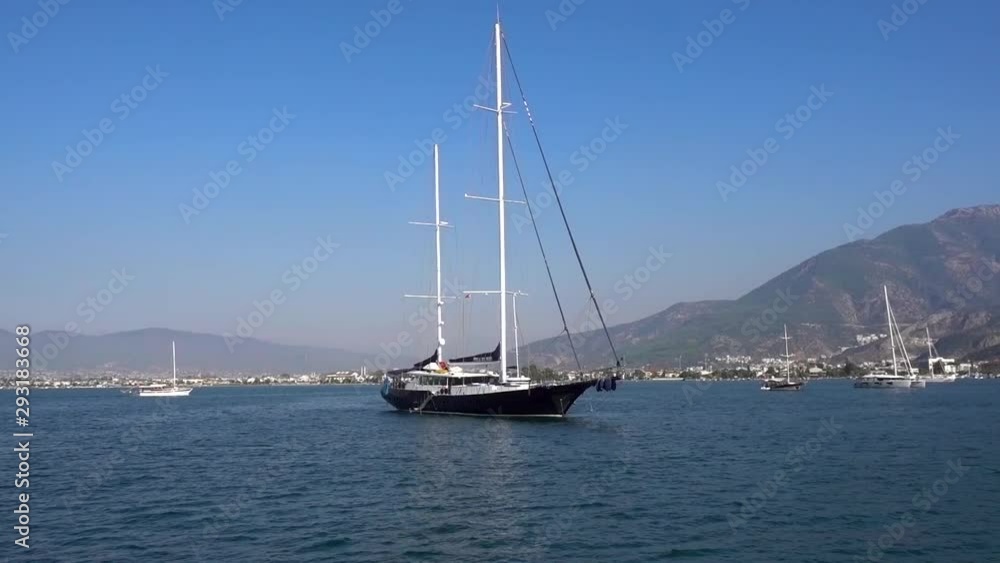 Beautiful big yacht anchored in the blue calm sea against the background of beautiful small mountains and ships on a Sunny summer day in Turkey. Beautiful big yacht anchored in the blue calm sea against the background of beautiful small mountains and ships on a Sunny summer day in Turkey.
