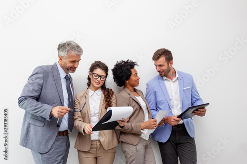 Group of four multiethnic business people standing in front of white wall