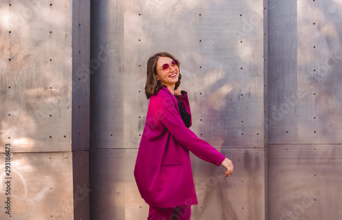 A girl in trendy plum and bright suit walks around the city and has fun. Style.