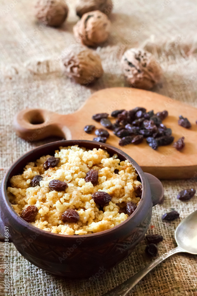 Sweet millet porridge with dark raisins in ceramic rustic bowl