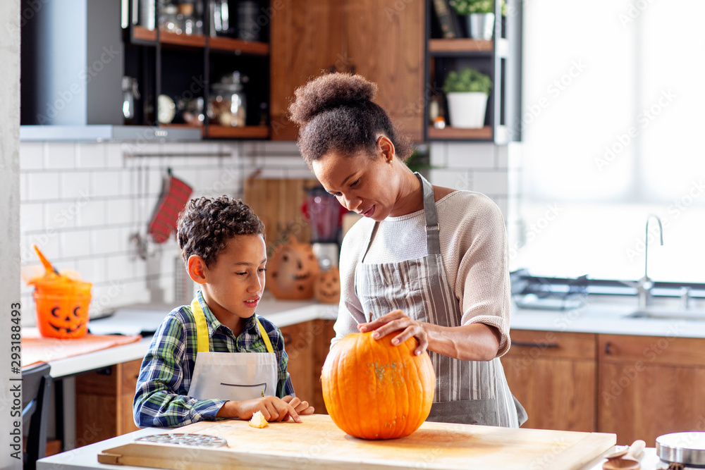 Woman with his son at the kitchen prepare pumpkin for halloween