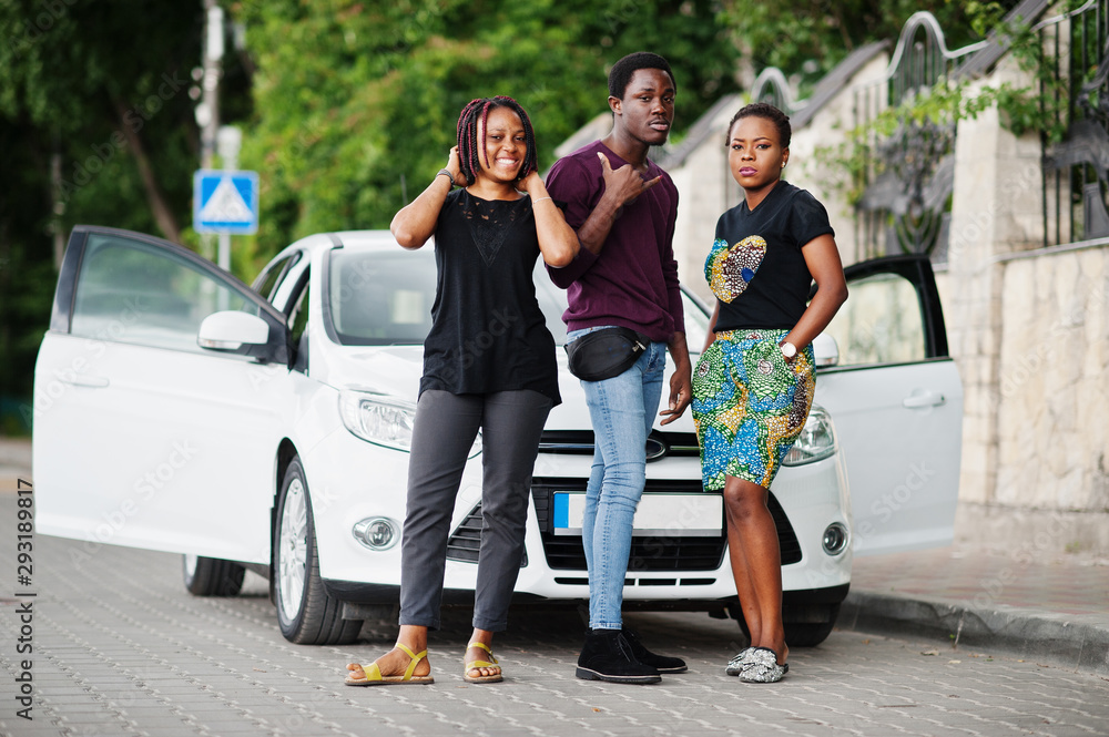 Three african american friends stay near car.