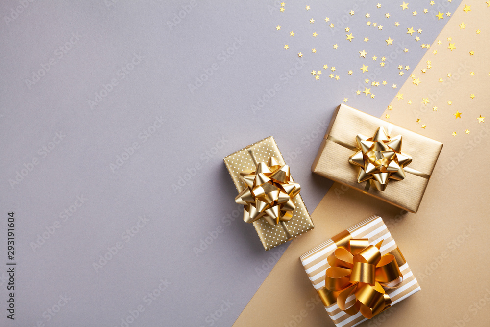 Golden gift or present boxes with golden bows and star confetti top view. Christmas background. Flat lay. - obrazy, fototapety, plakaty 
