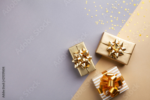 Golden gift or present boxes with golden bows and star confetti top view. Christmas background. Flat lay. photo