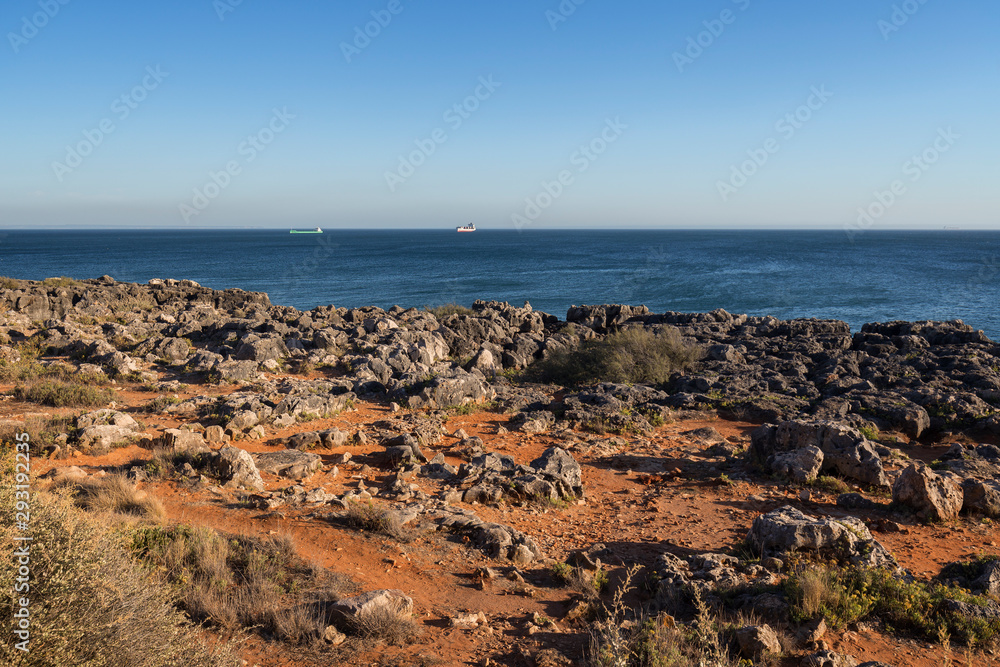 View of the Atlantic Ocean and Pedra da Nau, rocky coastal area in Cascais, Portugal, on a sunny day.