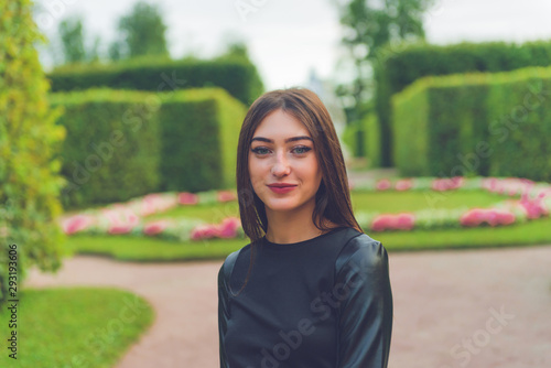 Beautiful happy smiling girl looking at you against trees in bokeh background. Attractive woman portrait outdoors.