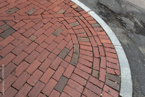 Weathered brick sidewalk beside crumbling asphalt street, horizontal aspect