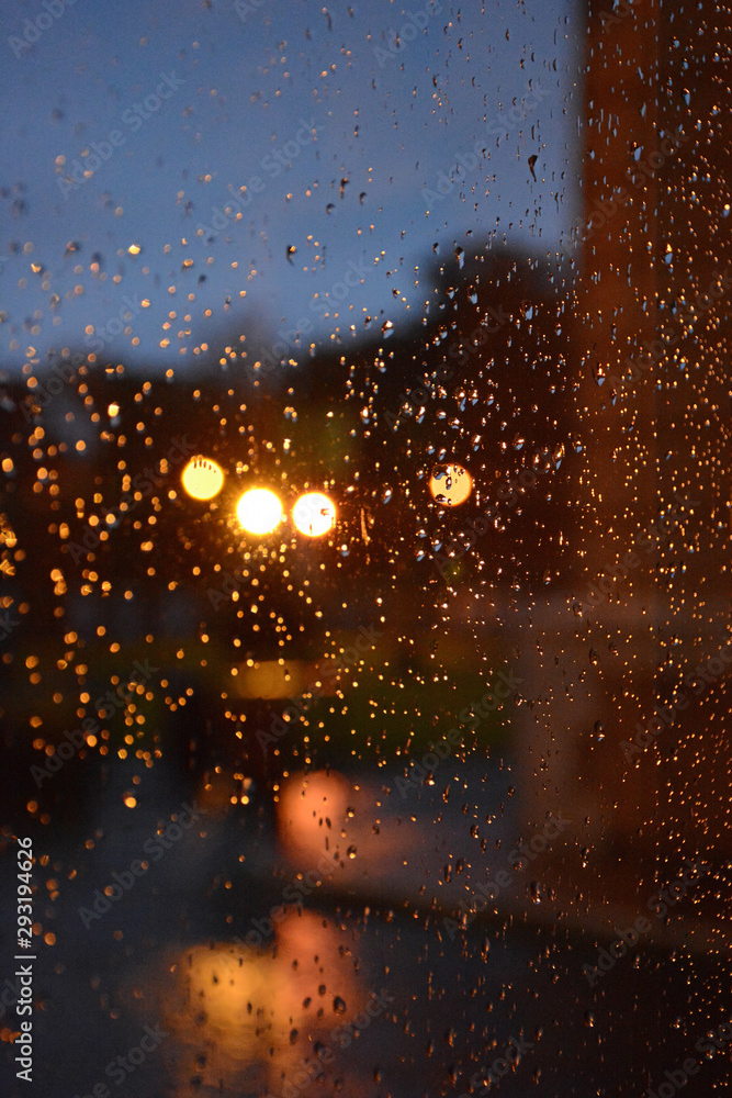 Rainy blurred autumn day concept. Raindrops on glass on night lights background