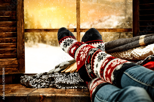Woman legs with wool socks and window space of winter time 