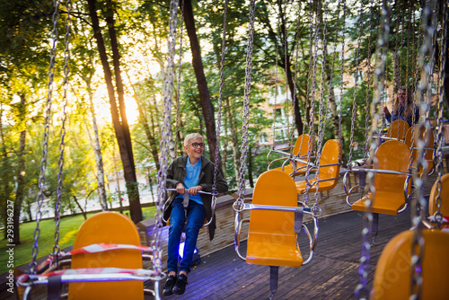Happy teenager boy riding on carousel in entertainment park