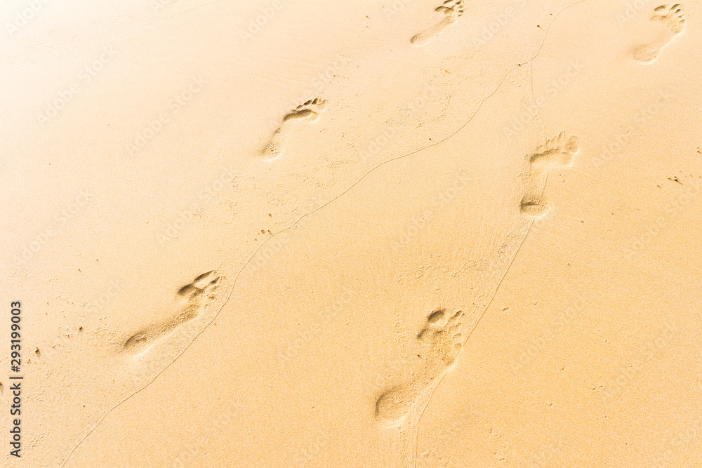 Barefoot footprints of two people in the sand, tropical beach or dune and desert background Barefoot footprints of two people in the sand, tropical beach or dune and desert background