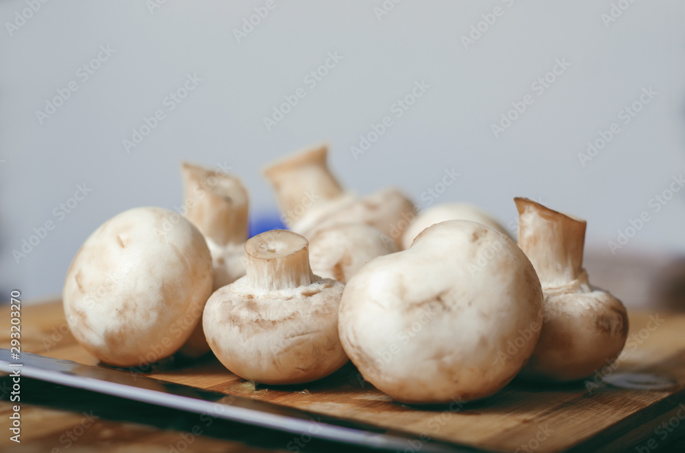 Woman cutting mushrooms on wooden plank, close up Woman cutting mushrooms on wooden plank, close up
