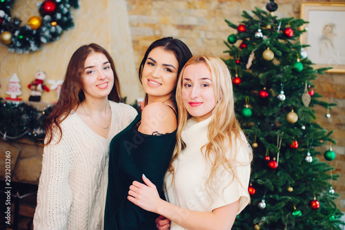 Three beautiful girls in a decorated room. Women near Christmas tree. Ladies in a sweaters