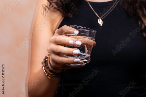 A closeup and front view on a young woman suffering from Parkinson's disease, the wrist and hand tremors whilst trying to drink, the disorder usually affects the elderly. photo