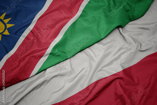 waving colorful flag of poland and national flag of namibia.