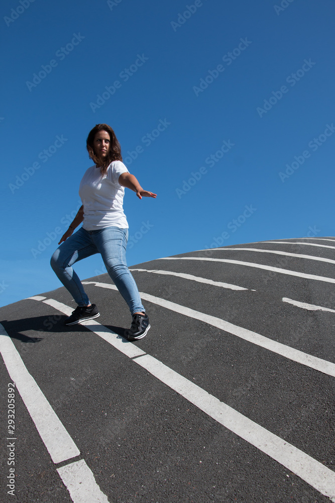 Confident woman posing over asphalt floor with white stripes Confident woman posing over asphalt floor with white stripes