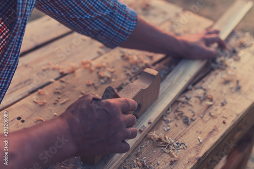 Hand of old carpenter male works on wood