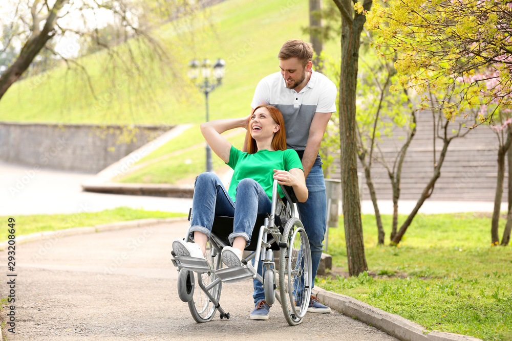Happy woman in wheelchair and young man at park on sunny day Happy woman in wheelchair and young man at park on sunny day