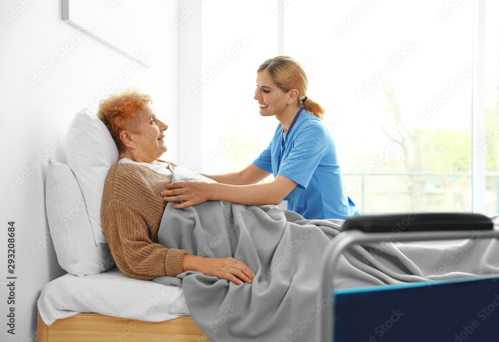 Obraz premium Nurse in uniform assisting elderly woman indoors