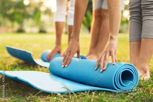 Fototapeta Naklejka Na Ścianę i Meble -  People rolling up yoga mat in park at morning, closeup