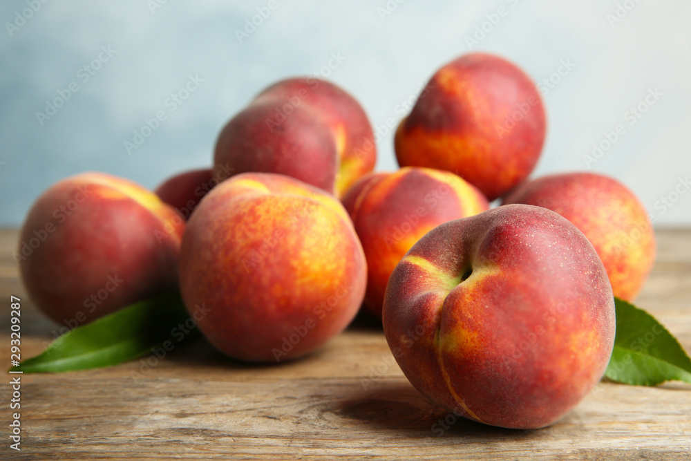 Fresh juicy peaches and leaves on wooden table against blue background Fresh juicy peaches and leaves on wooden table against blue background