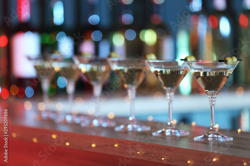 Glasses of martini cocktail with olives on counter in bar