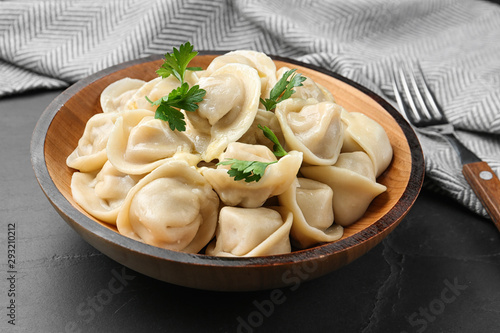 Tasty dumplings with parsley in bowl on black table