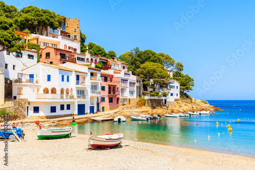 Fishing boats on beach in Sa Tuna village with colorful houses on shore, Costa Brava, Catalonia, Spain