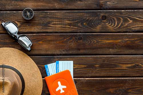 Tourist concept. Passport with airplane, tickets, hat, glasses on dark wooden background top view copy space frame