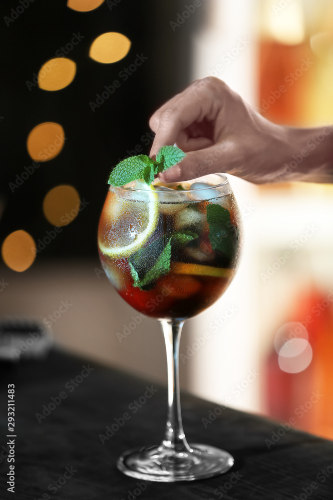 Fototapeta premium Woman preparing fresh alcoholic cocktail with lemon and mint at bar counter, closeup