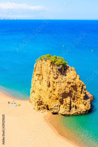 Rock in sea known as Isla Roja on beautiful Cala Moreta beach and view of blue sea, Costa Brava, Catalonia, Spain