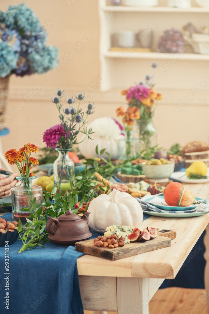 Festive autumn table with flowers in vaze, white pumpkin and vegetables