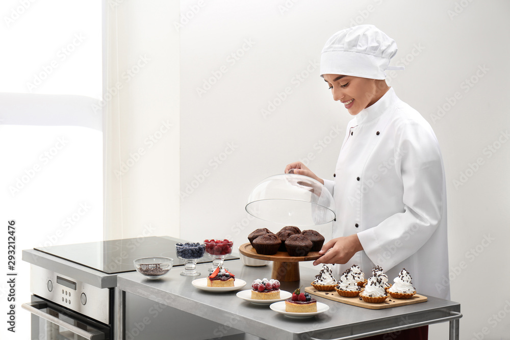 Female chef with pastries at table in kitchen Female chef with pastries at table in kitchen