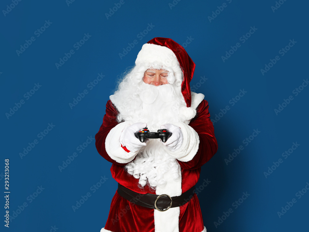 Authentic Santa Claus with game controller on blue background. Space for text Authentic Santa Claus with game controller on blue background. Space for text