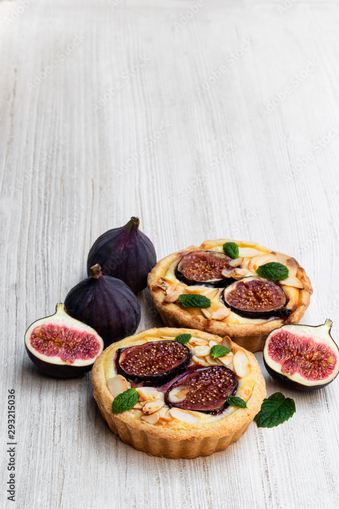 Homemade fig tartles with brie cheese and almonds on white wooden table Homemade fig tartles with brie cheese and almonds on white wooden table