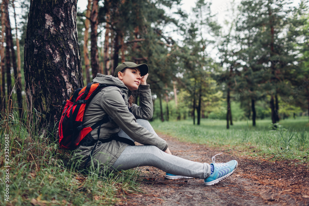 Woman tourist resting in autumn forest sitting by tree. Traveling and tourism concept Woman tourist resting in autumn forest sitting by tree. Traveling and tourism concept