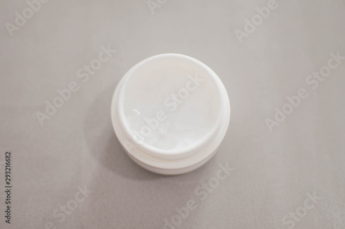 A beauty cream on a plastic container on a gray background