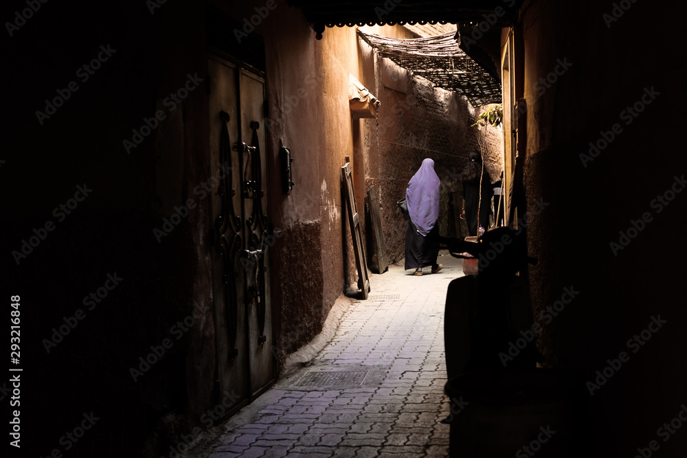 Moroccan Woman Walking Down A Narrow Alley In Jamaa El Fnaa Market Square, Marrakesh, Morocco Moroccan Woman Walking Down A Narrow Alley In Jamaa El Fnaa Market Square, Marrakesh, Morocco