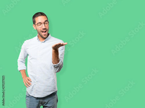 Surprised young man holding something with his hand