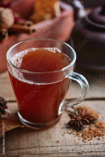 Hot black ceylon tea in glass cup on wooden table on the background of box with cone and spices