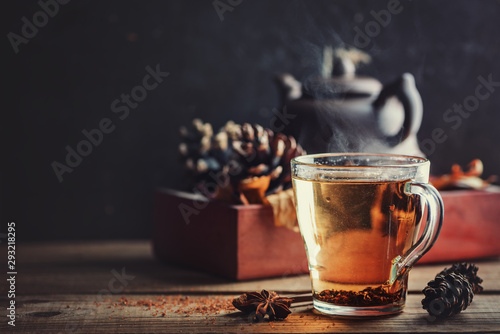 Black tea in glass cup on wooden table on the background of box with cone