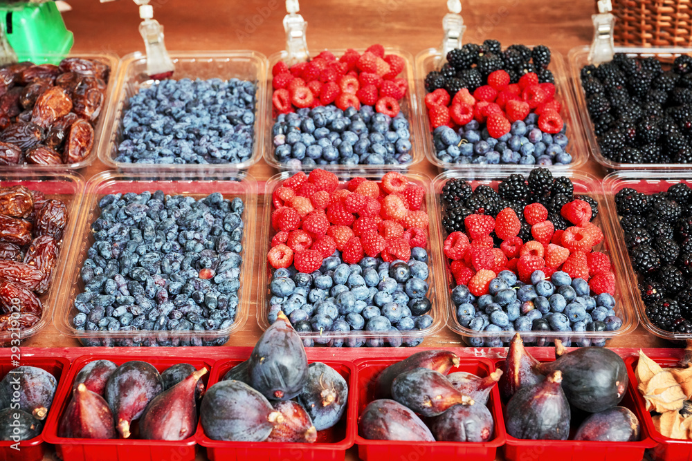 Fresh blueberries, raspberries, blackberries, figs and dry plums displayed in plastic containers on an outdoor market stall Fresh blueberries, raspberries, blackberries, figs and dry plums displayed in plastic containers on an outdoor market stall