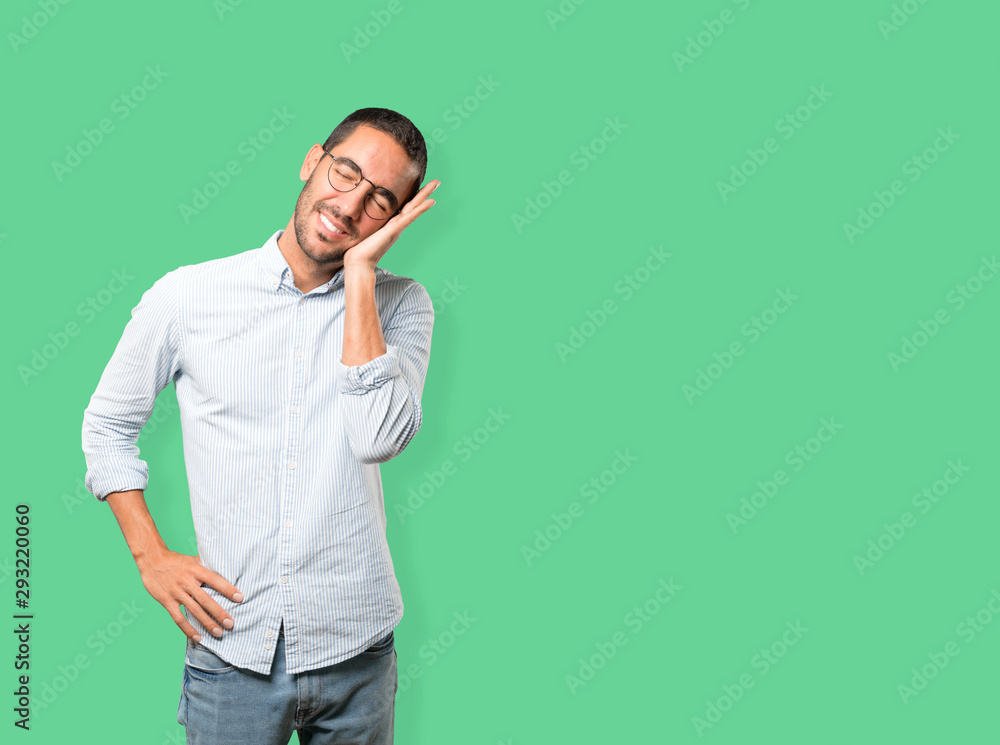 Relaxed young man making a gesture of sleep Relaxed young man making a gesture of sleep