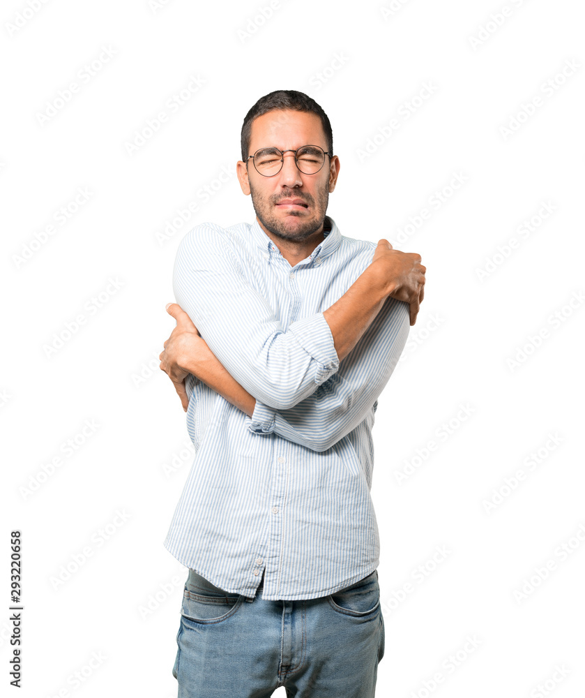 Concerned young man making a gesture of being cold Concerned young man making a gesture of being cold
