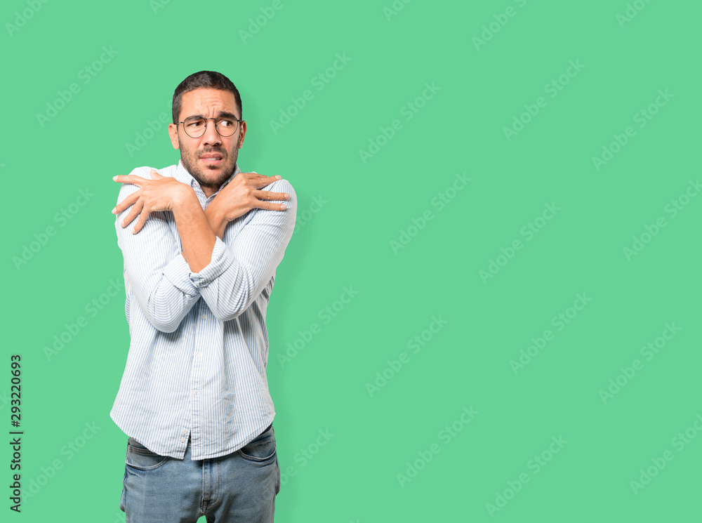Concerned young man making a gesture of being cold Concerned young man making a gesture of being cold