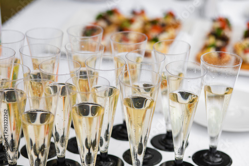 View from above of glasses with champagne served on table near appetizers on wedding celebration. Canapes at background. Concept of catering, party and restaurant.