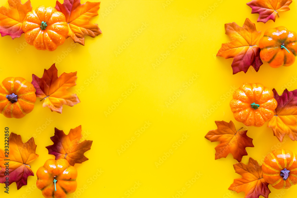 Autumn frame with colorful leaves and pumpkins on yellow background top view space for text Autumn frame with colorful leaves and pumpkins on yellow background top view space for text